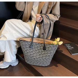 Detail of black and white woven tote bag with leather straps and zip closure