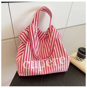 Close-up of pink striped canvas tote bag with Cupere text on a wooden desktop