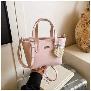 Detailed view of pink PU leather handbag with elegant pearl heart charm and metal plaque