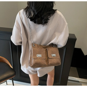 Vue arrière d'un mannequin portant un sac vintage marron avec des chaînes argentées