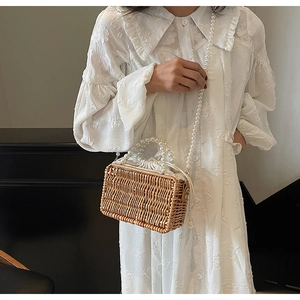 Detail of woven straw box bag with premium white pearl beaded handle and drawstring lining