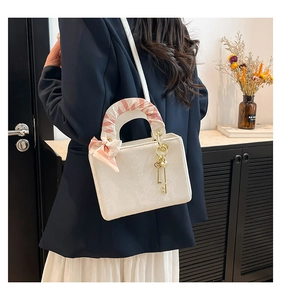 Vue détaillée du sac à main blanc carré avec poignée en soie et breloque dorée