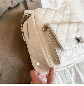 Detail view of cream quilted backpack featuring silver twist lock and metal chain strap