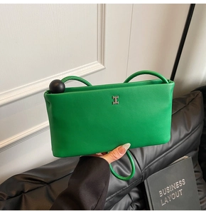 Dettaglio della borsa quadrata in pelle verde con logo H in metallo e decoro a sfera