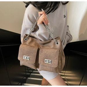 Détail d'un sac cabas vintage marron avec deux poches frontales et chaîne en argent