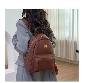 Detail of vintage dark brown faux leather backpack featuring adjustable woven straps and gold hardware