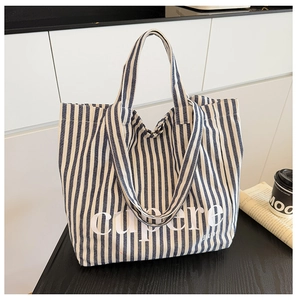 Detail of blue and white striped canvas tote bag with wide shoulder strap for daily commute