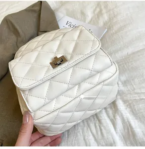 Detail shot of white quilted faux leather backpack with metallic turn-lock closure