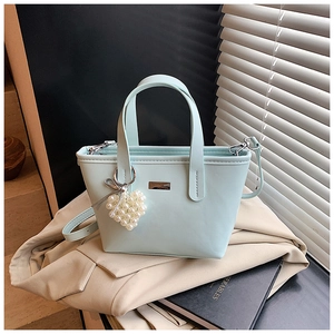 Detail of mint green bucket bag with pearl heart charm and metallic silver accents