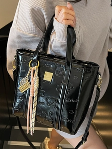 Glossy black embossed bucket bag with cute cartoon motifs and decorative charms for women