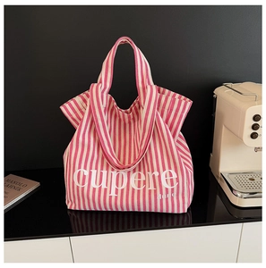 Detail view of pink and white striped canvas tote bag with lettering on a sleek surface