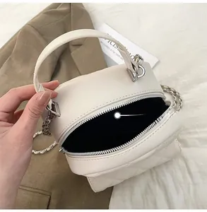 Detail view of the white quilted mini cylinder bag interior with silver chain strap
