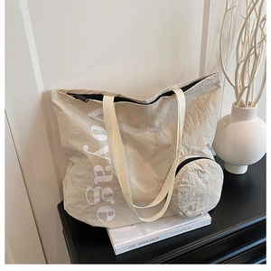 Détail du sac cabas en tissu lavé beige avec texte voyage et petit porte-monnaie rond