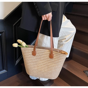 Detail of hand-woven straw tote bag with brown leather straps for commuting and vacation