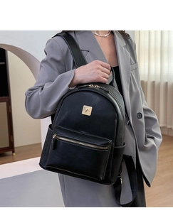 Close-up of black lychee leather backpack featuring MH BV logo and gold zipper detail