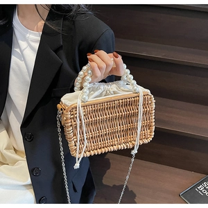 Detail of woven straw handbag featuring elegant faux pearl handle and drawstring pouch