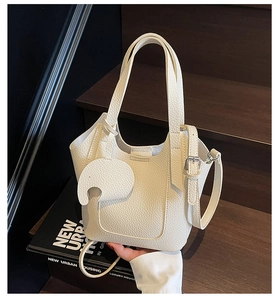 Close-up of white lychee leather bucket bag with cute elephant charm and thin strap