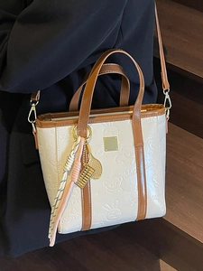 Embossed cream bucket bag with brown straps and cute rabbit patterns shown on a person