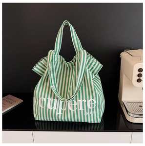 Detail of green and white striped canvas tote bag featuring cupere dune text logo