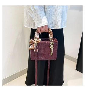 Détail du sac à main rouge foncé motif serpent avec foulard en soie sur la poignée