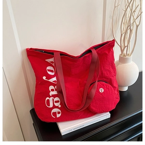 Détail du sac fourre-tout rouge délavé avec imprimé voyage et petit porte-monnaie assorti