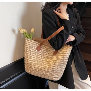 Detail of large woven straw tote bag featuring brown leather handles and a floral lifestyle scene