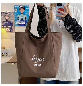 Detail of canvas tote bag with white beyou merci print and leopard strap accents