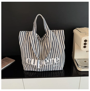 Detail of blue and white striped canvas tote bag with dual straps and letter print