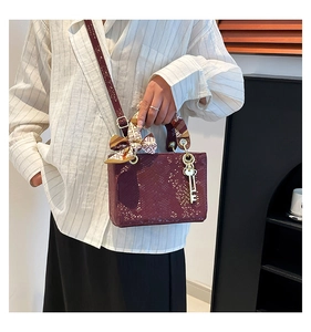 Détail du sac bordeaux à motif écailles, poignée en foulard de soie et pendentif clé