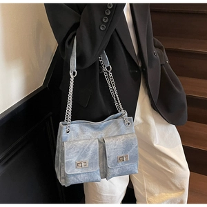 Détail du sac à bandoulière en denim bleu clair avec chaînes et poches à fermoir