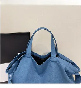 Detail showing the sturdy denim top handles and secure zipper closure on blue tote bag