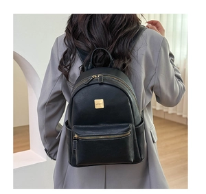 Detail of a vintage black backpack with white contrast stitching and gold metal hardware