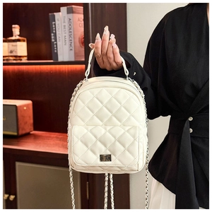 Detail of cream quilted mini backpack with chain strap and metal turn-lock closure