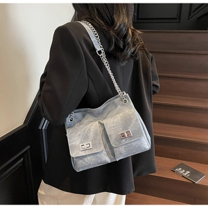 Détail d'un sac cabas en denim avec bandoulière chaîne et poches à fermoir tournant