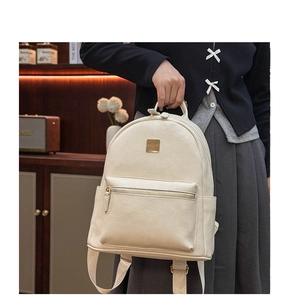 Detail of a chic beige faux leather backpack with gold logo and front zipper pocket