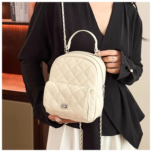 Detail of quilted diamond pattern and silver twist lock on a beige mini backpack