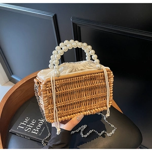Close-up of woven rattan bag with elegant large pearl handles and canvas drawstring