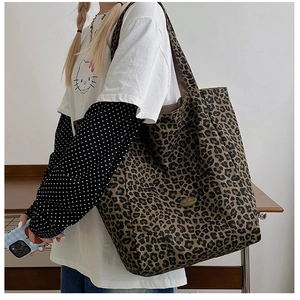 Close-up of large leopard print tote bag with metal logo and slim shoulder straps