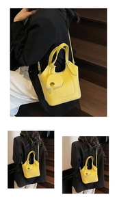 Close-up of a yellow lychee pattern leather bucket bag with an elephant charm on stairs