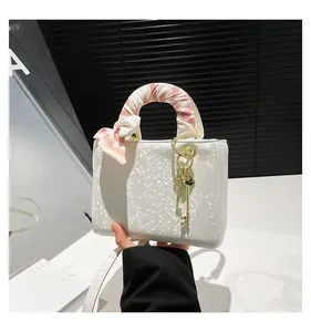 Détail du sac à main blanc nacré texture écailles avec foulard en soie et pendentif