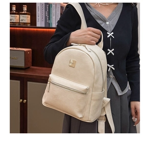 Side view of cream white leather backpack featuring gold zippers and fabric straps