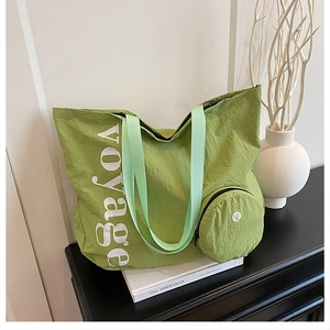 Détail du sac cabas vert en tissu délavé avec texte voyage et petite pochette ronde jointe