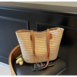 Detail view of woven straw tote bag with brown leather straps and rural style textures