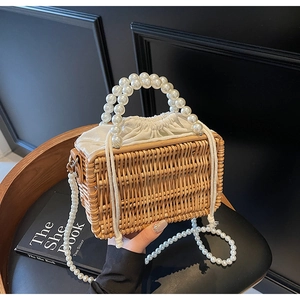 Detail of woven straw bag with luxury white pearl top handles and drawstring lining