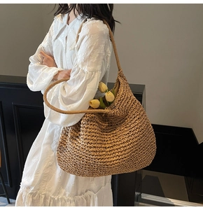 Close-up of khaki straw hobo bag showing detailed woven texture and sturdy shoulder strap
