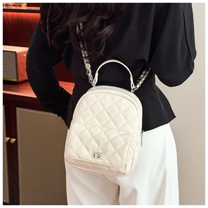 Detail of a quilted beige mini backpack with chain straps and metal twist lock