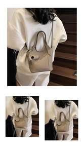 Close-up of elephant grey pebble leather bucket bag with cute elephant charm and strap