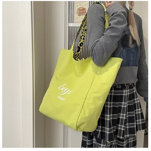 Detail of large tote bag in neon yellow featuring leopard print strap and logo print