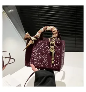 Détail du sac à main bordeaux à motif serpent avec foulard en soie et pendentif clé