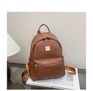 Macro detail of brown leather backpack with golden metal logo and dual zipper closure